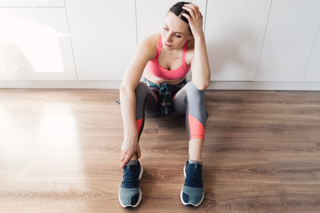 a woman sits on the floor touching her head